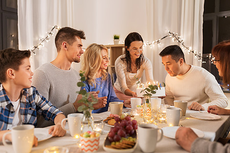 庆祝家庭快乐的男人家里的晚餐聚会上生日蛋糕上的蜡烛幸福的家庭家里举行生日聚会图片