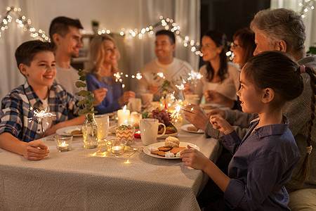 庆祝,节日诞节的快乐的家庭与火花家里的晚餐聚会上玩得很开心家里闪闪发光的人家里举行晚宴图片