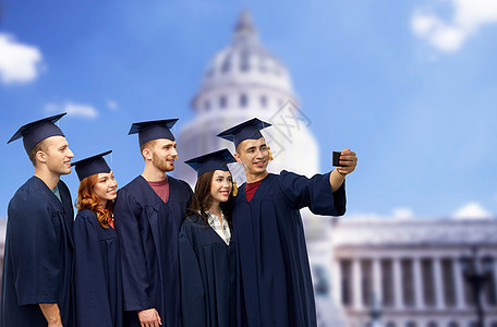教育,毕业人的群快乐的研究生砂浆板学士学位礼服采取自拍智能手机白色背景毕业生用智能手机自拍图片