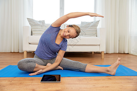 健身,运动健康的生活方式妇女与平板电脑电脑瑜伽练垫子家里家里平板电脑瑜伽的女人图片