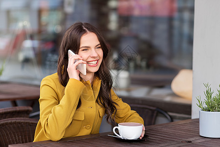 通信技术休闲人的快乐的轻妇女十几岁的女孩打电话给智能手机,城市街道咖啡馆露台喝热巧克力十几岁的女孩城市咖图片