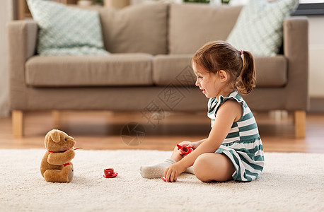 童人的快乐的三岁女婴玩茶玩具陶器泰迪熊家里小女孩家玩玩具茶具图片