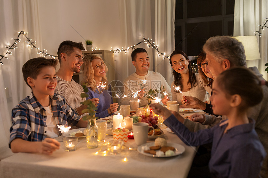 庆祝节日诞节的快乐的家庭与火花家里的晚餐聚会上玩