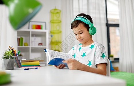 童享好音乐教育,童技术快乐的男孩耳机阅读书家里男孩戴着耳机,家学课本背景