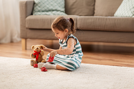 童人的快乐的三岁女婴玩茶玩具陶器泰迪熊家里小女孩家玩玩具茶具图片