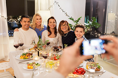庆祝,假日人们的幸福的家庭家里举行晚餐聚会,并智能手机拍照晚宴上用智能手机拍摄家庭照片图片