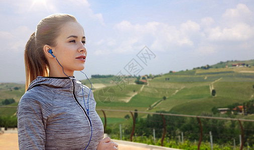 健身,运动,人,技术生活方式的快乐的女人跑步听音乐耳机乡村景观背景戴耳机的女运动员户外跑步图片