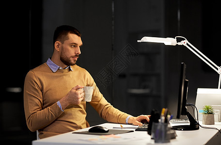商业,截止日期技术男人电脑工作喝咖啡夜间办公室带笔记本电脑咖啡的男人夜间办公室工作图片