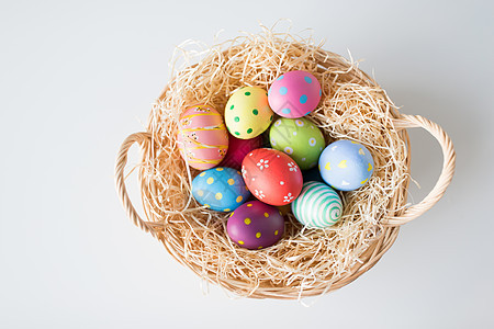 复活节,假日传统彩色鸡蛋篮子与稻草白色背景篮子里的彩色复活节彩蛋图片