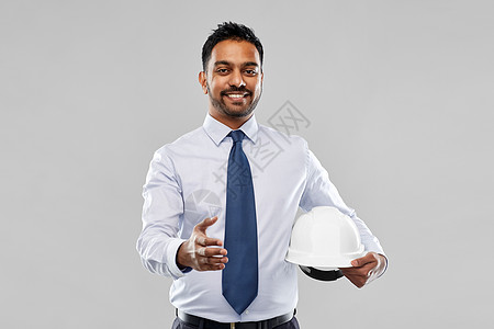 建筑,建筑业务建筑微笑的印度建筑师商人与头盔伸展手握手灰色背景带头盔的建筑师握手背景图片