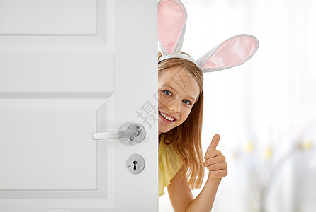 复活节,假日人们的快乐的女孩戴着兔子的耳朵偷看门外,家里竖大拇指快乐的女孩,复活节兔子的耳朵偷看门外图片