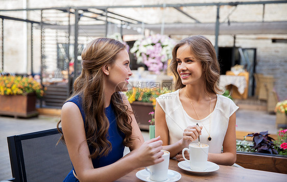 沟通友谊的微笑的轻妇女街头咖啡馆喝咖啡微笑的轻女人街头咖啡馆喝咖啡图片