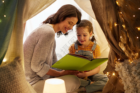 家庭,潮格人的快乐的母亲小女儿孩子们的帐篷里家里晚上看书孩子们家帐篷里快乐的家庭读物图片