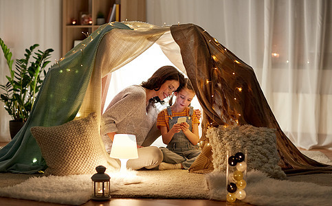 家庭,技术快乐的母亲小女儿与智能手机孩子们的帐篷晚上家家庭幸福,智能手机孩子们的帐篷里图片
