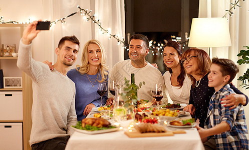 庆祝,假日人们的快乐的家庭家里举行晚餐聚会,并智能手机自拍家人举行晚宴自拍图片
