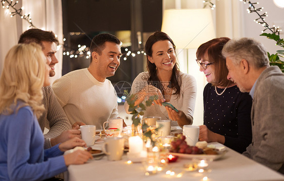 庆祝,假日人们的幸福的家庭与智能手机家里举行茶话会家里智能手机的幸福家庭图片