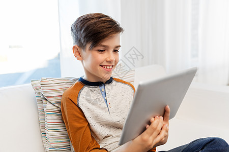 童,技术人的微笑的男孩与平板电脑坐沙发上家微笑的男孩家里用平板电脑电脑图片