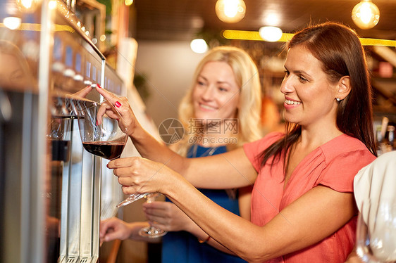 人们,酒精生活方式的快乐的女人用璃倒红酒酒吧餐馆的配药机快乐的女人酒吧的饮水机里倒酒图片