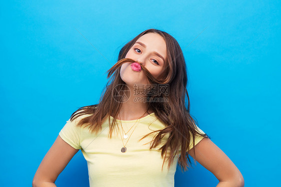 发型人的轻的女人十几岁的女孩胡子与缕头发明亮的蓝色背景轻的女人用头发胡子图片