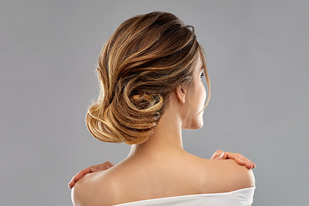 人背后美丽人的轻的女人,赤裸的肩膀背后灰色的背景来自灰色背景的轻