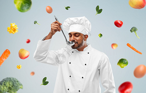 烹饪,专业健康的饮食快乐的印度男厨师品尝食物勺子蓝色背景蔬菜快乐的印度男厨师品尝食物瓢图片