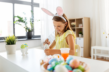 复活节,假日人们的快乐的女孩戴着兔子耳朵,头带着色鸡蛋与颜色刷子家里快乐的女孩家里给复活节彩蛋着色图片