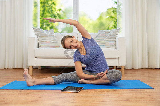 健身,运动健康的生活方式妇女与平板电脑电脑瑜伽练垫子家里家里平板电脑瑜伽的女人图片
