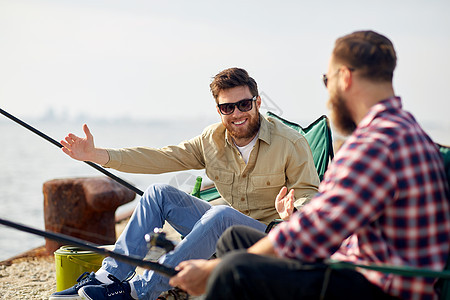 休闲人的快乐的男朋友与杆码头上的海上讲述捕鱼的故事快乐的男朋友与棒谈论钓鱼图片