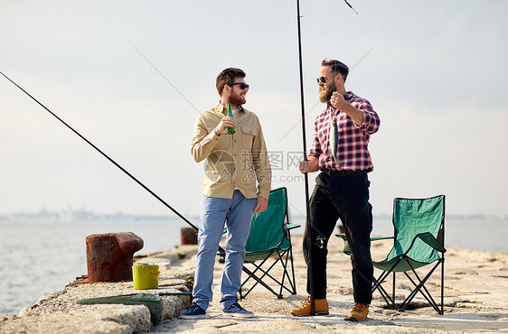 休闲人们的快乐的朋友与钓鱼竿,鱼啤酒码头上交谈海上码头上钓鱼竿啤酒的快乐朋友图片