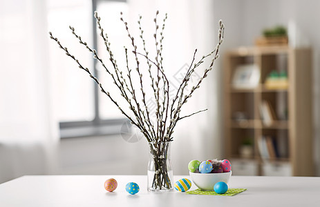 桌子上银柳枝彩色复活节彩蛋背景图片
