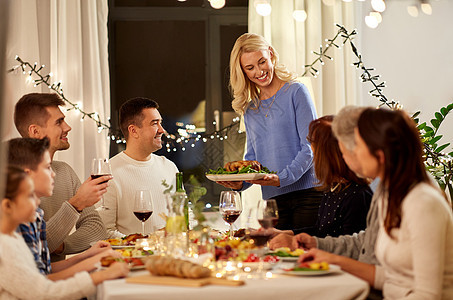 庆祝,节日人们的快乐的女人提供烤鸡给家庭家里举行晚餐聚会幸福的家庭家里举行晚宴图片