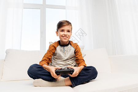 游戏,技术人的微笑男孩与游戏垫家里玩电子游戏快乐的男孩家里玩电子游戏背景图片