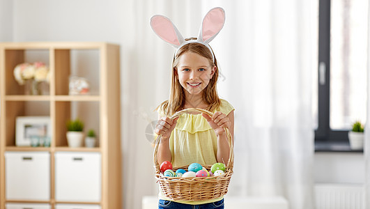 复活节,假日人们的快乐的女孩戴着兔子耳朵,头带着篮子彩色鸡蛋家里家里彩色复活节彩蛋的快乐女孩图片