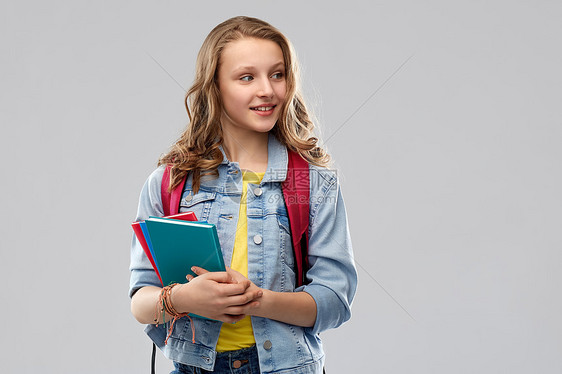 教育,学校人的快乐微笑的十几岁的学生女孩带着灰色背景的书包书带着书包的快乐微笑的十几岁的学生女孩图片