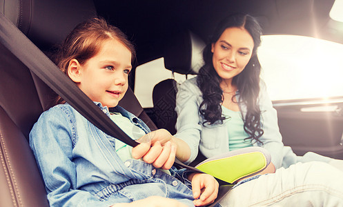 家庭,交通,道路旅行人们的快乐的女人系着孩子的安全安全带车里快乐的女人车里用安全带系着孩子图片