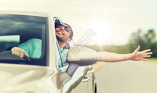 男人戴着太阳镜,开着车快乐的驾驶汽车挥手图片