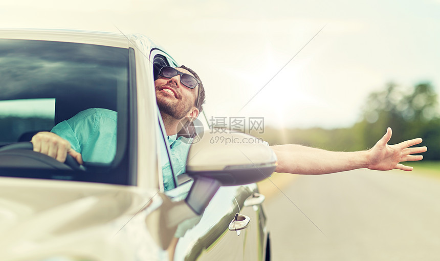 男人戴着太阳镜,开着车快乐的驾驶汽车挥手图片
