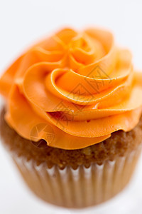 食物,糕点糖果的纸杯蛋糕与橙色奶油霜白色背景用奶油霜把纸杯蛋糕收来图片