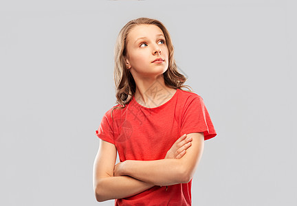 人们的十几岁的女孩穿着红色T恤,交叉手臂,灰色背景下向边看十几岁的女孩穿着红色T恤,双臂交叉图片