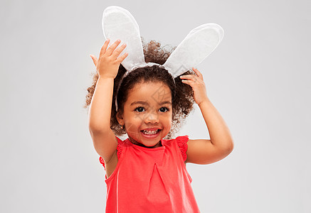 童,派道具复活节快乐的非裔美国女孩戴着兔子耳朵头巾灰色的背景快乐的小女孩戴着复活节兔子的耳朵图片