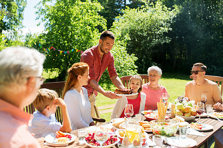 休闲,假日人们的快乐的家庭夏季花园举行节日晚餐烧烤聚会家人夏天的花园里吃晚饭烧烤图片