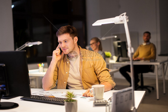 商业,截止日期技术男人与电脑呼叫智能手机夜间办公室男人夜间办公室打电话给智能手机图片