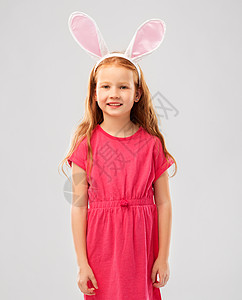 复活节,假期童的快乐的红头发女孩戴着兔子耳朵头巾灰色的背景快乐的红头发女孩戴复活节兔子耳朵图片