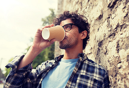 生活方式,饮料人的戴眼镜的人喝咖啡次纸杯石街墙戴眼镜的男人街上的墙上喝咖啡图片