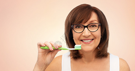 微笑的妇女使用牙刷护理牙齿图片