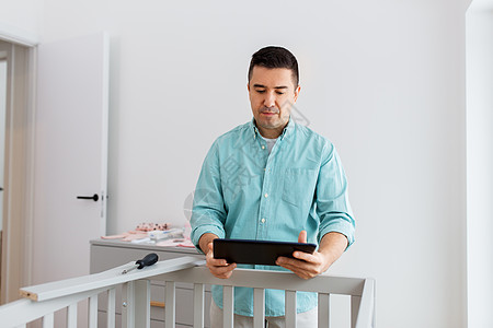 父母,父亲托儿所的中父亲与平板电脑电脑装婴儿床家里父亲用平板电脑装婴儿床家图片
