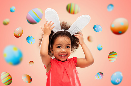 童,派道具复活节快乐的小非裔美国女孩戴着兔子耳朵头巾彩色鸡蛋上生活的珊瑚背景快乐的小女孩戴着复活节兔子的耳朵图片