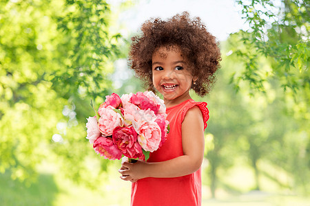 童人的快乐的小非裔美国女孩与花绿色的自然背景快乐的非裔美国女孩带着花图片
