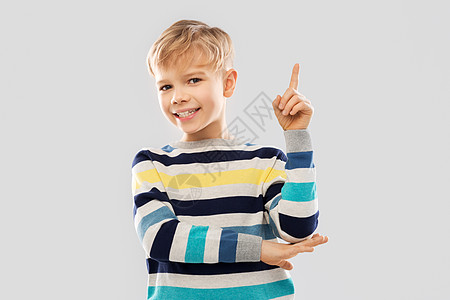童,表情人的小男孩穿着条纹套头衫,手指指向灰色背景穿条纹套衫的小男孩指着手指图片