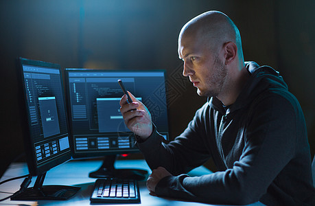 网络犯罪,黑客技术男黑客与智能手机进度加载栏的计算机屏幕黑暗的房间黑客带着智能手机电脑黑暗的房间里图片